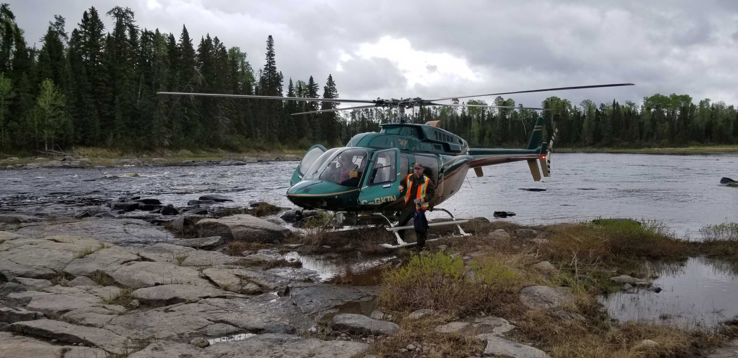 A parked helicopter in Marten Falls with Field Studies personnel exiting the aircraft.