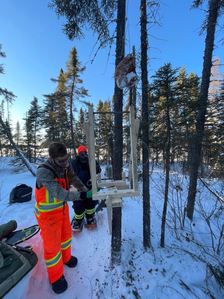 Two people outside in winter building a hair snag device