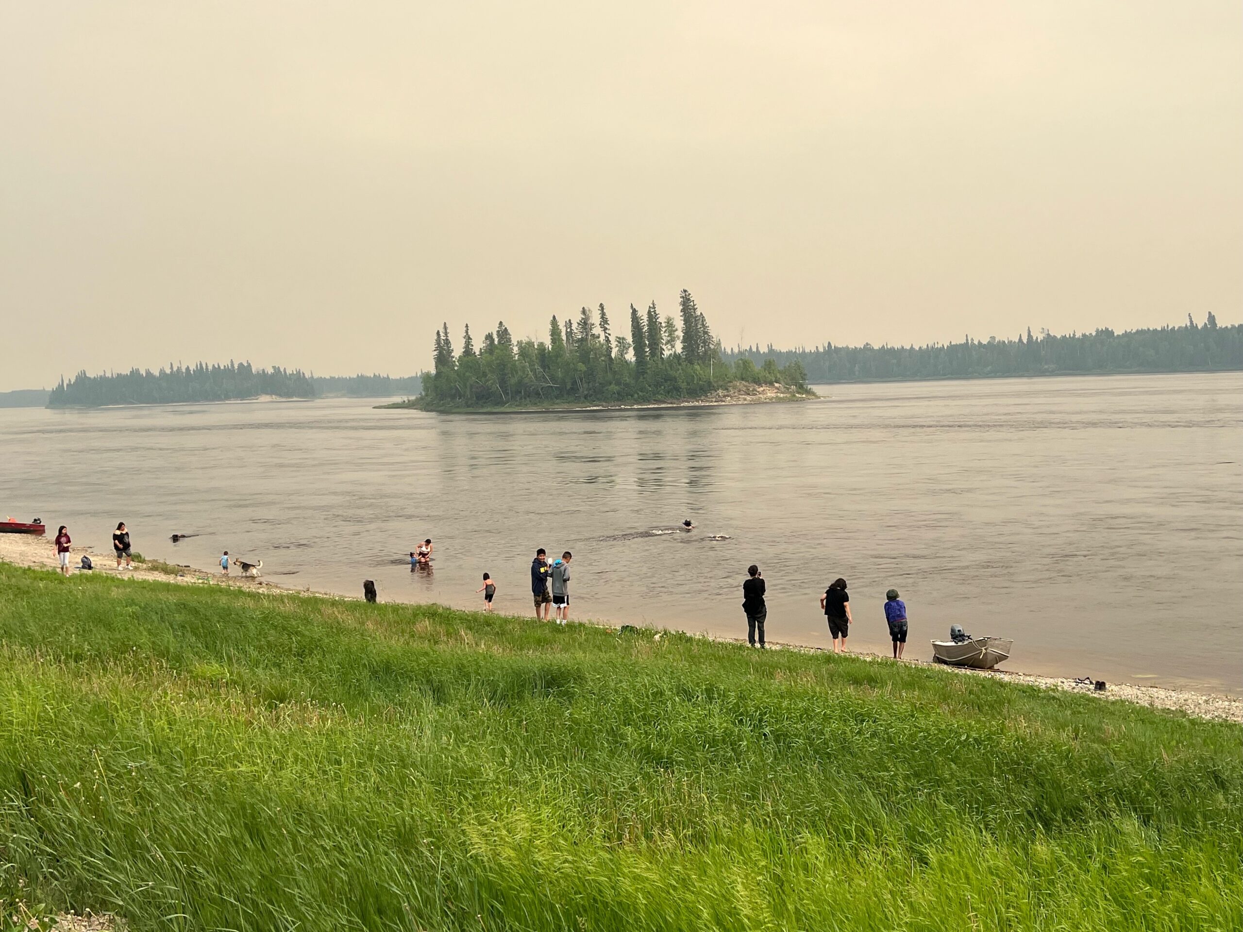 People spending time on the shore of a river in Marten Falls First Nation.