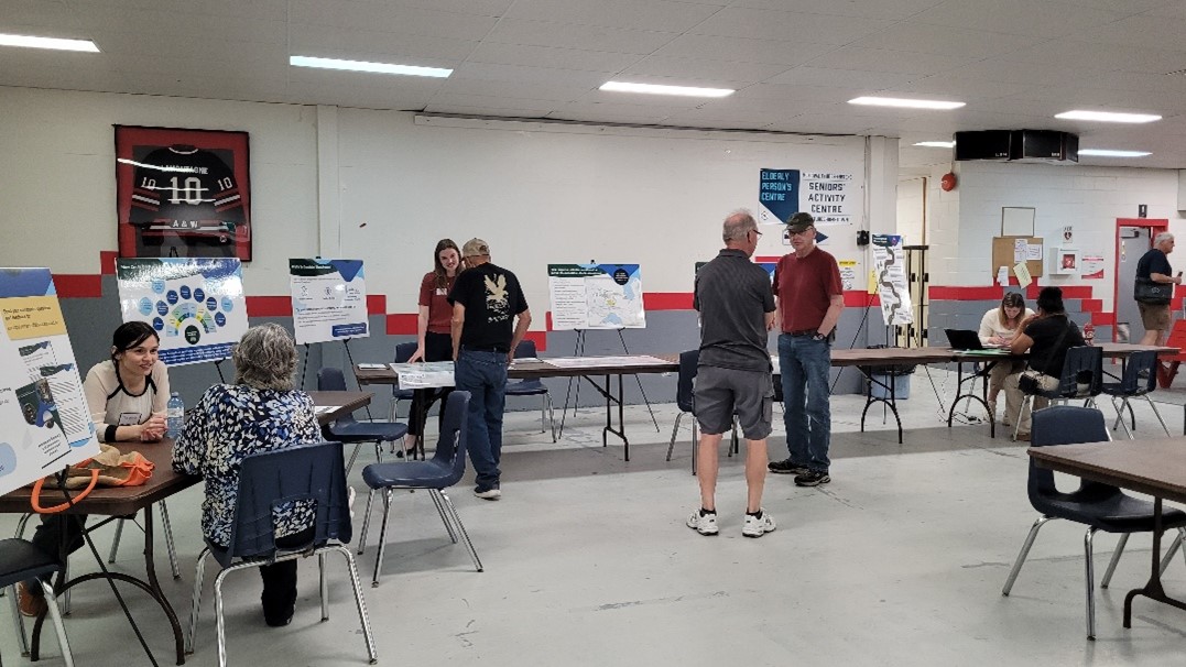 3. Photo of people talking in Geraldton Recreation Centre with tables and posters.