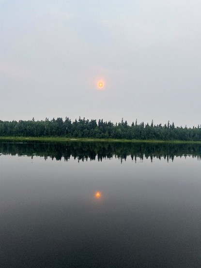 Photo of a sun over the trees and river in Marten Falls First Nation. Photo of a sun over the trees and river in Marten Falls First Nation.