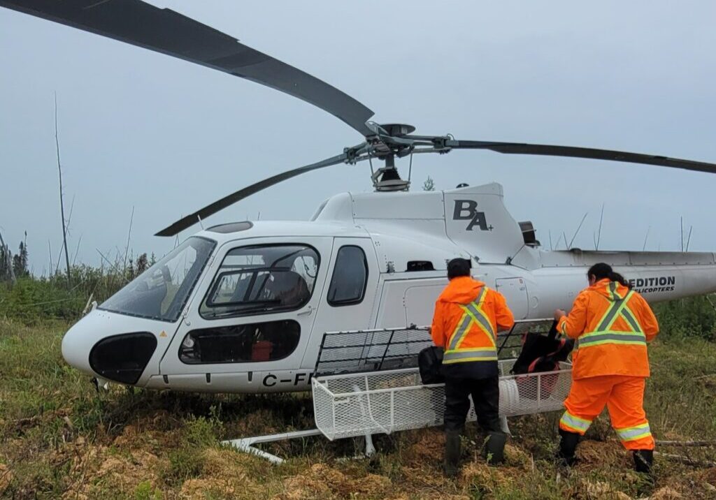 Two field crew members loading equipment into a helicopter